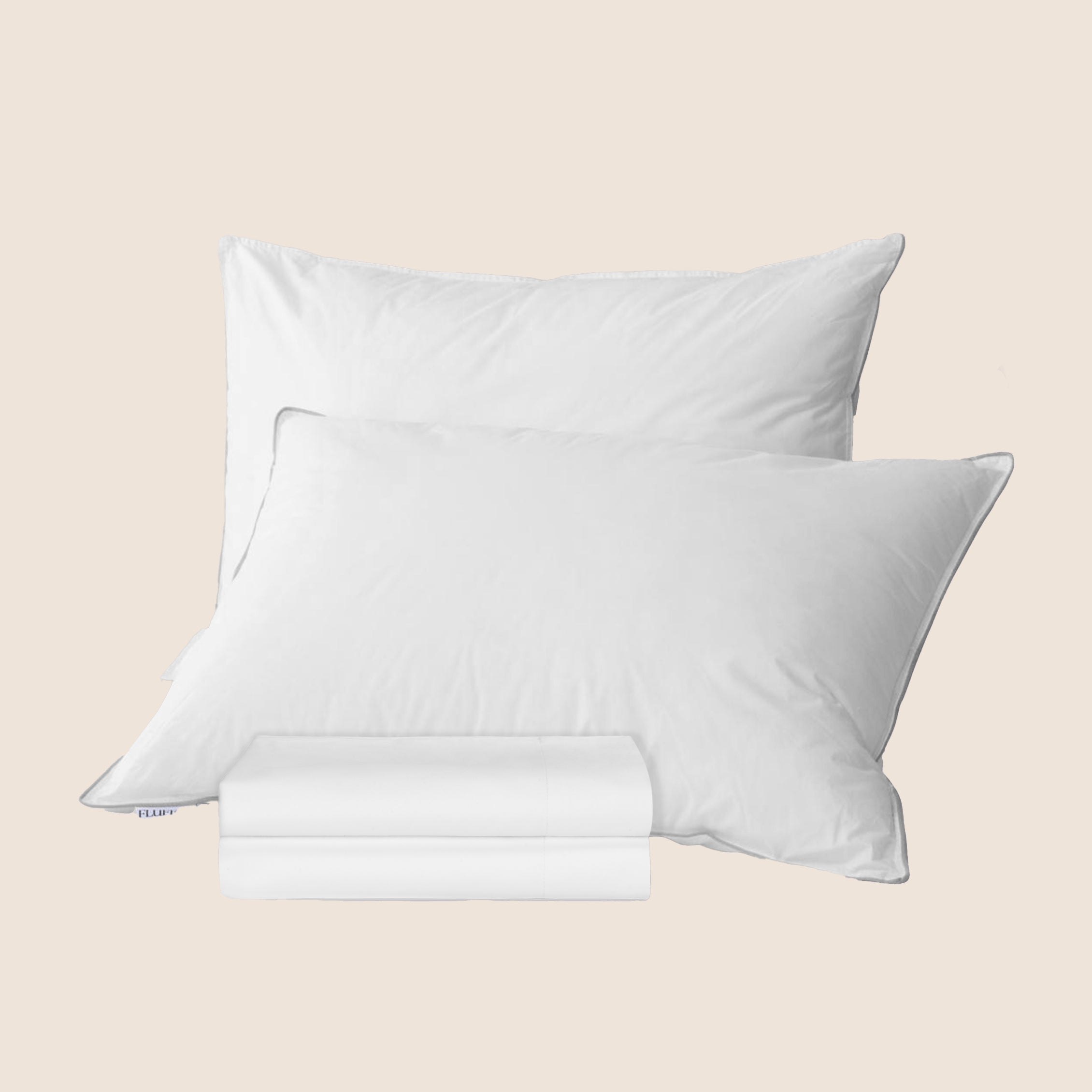 Two white pillows with a folded white pillowcase set in front
